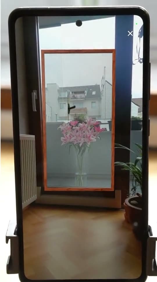 A phone on a tripod pointed at a real window, with the AR squeegee moving across the glass on screen